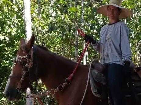 Lôids de chapéu de palha, montando a cavalo entre as árvores