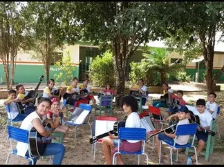 Alunos com violões numa aula ao ar livre na escola rural